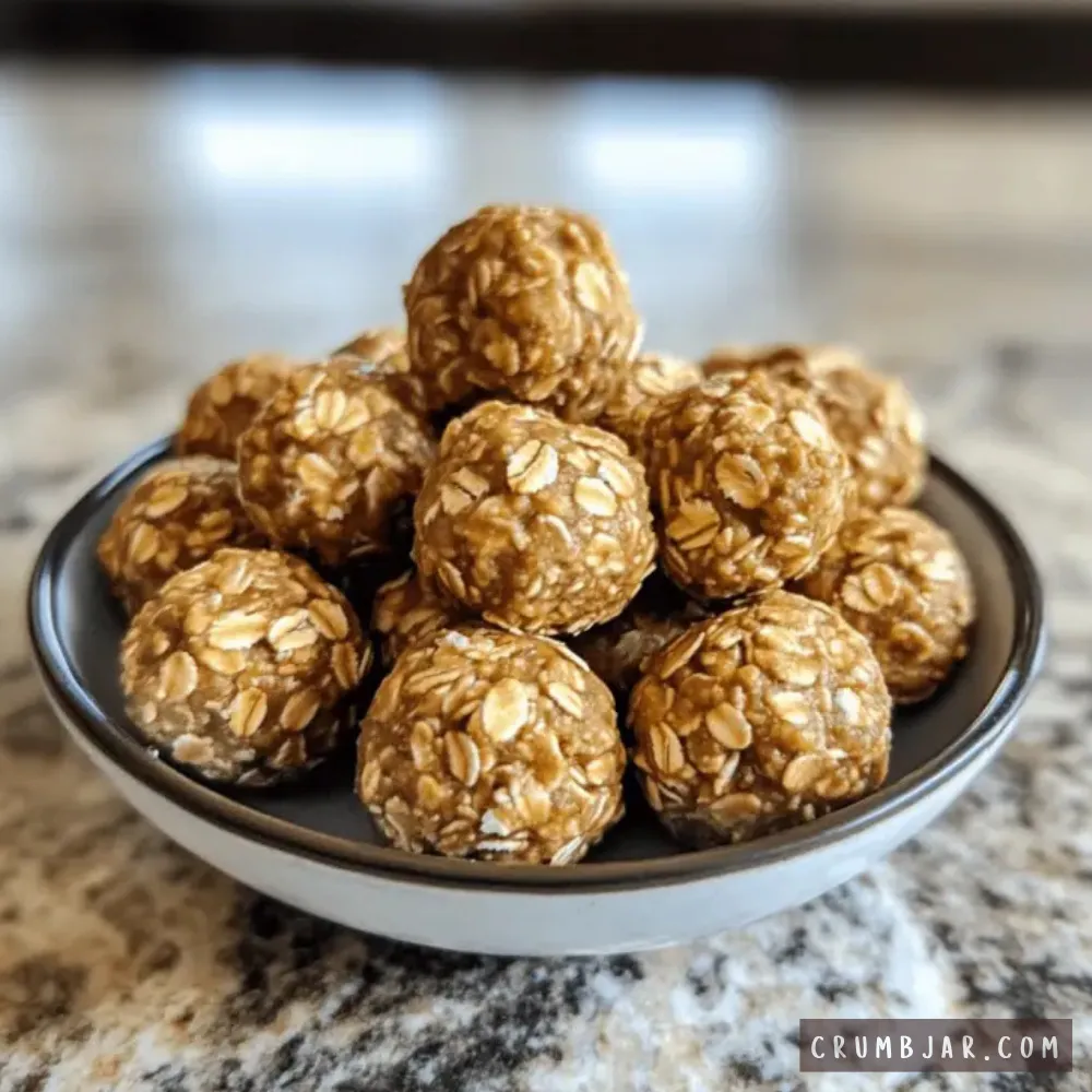 Stack of round, no-bake peanut butter oat energy bites piled in a small grey bowl on a granite countertop.