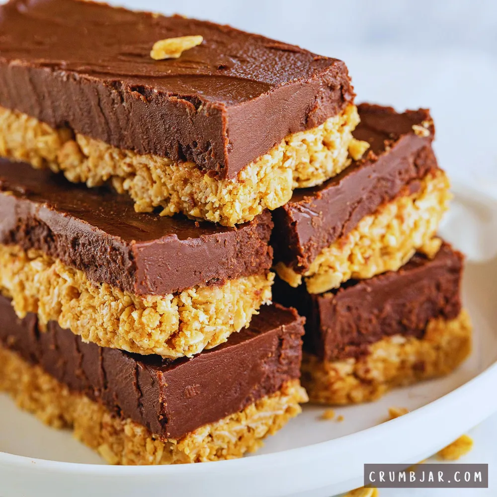 Stack of layered no-bake chocolate peanut butter bars with an oat peanut butter base and thick chocolate fudgy topping.