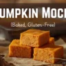 Baked gluten-free pumpkin mochi squares stacked on parchment paper, featuring overlay text reading "Pumpkin Mochi (Baked, Gluten-Free)".