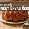 A freshly baked golden-brown monkey bread dripping with caramel syrup on a white plate, with text overlay reading "Homemade Monkey Bread Recipe".
